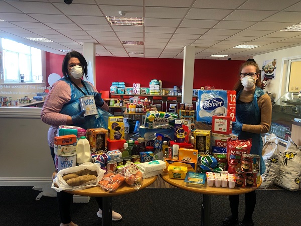 Compassion in Action staff members Louise O'Brien and Thea Compton-Jones stand with food that has been donated to help feed isolated families in need